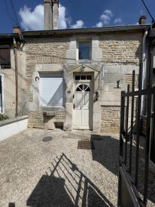 une maison en pierre avec une porte blanche et un portail dans l'établissement La Maison des Pressoirs, à Châteauvillain