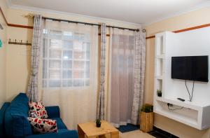 a living room with a blue couch and a window at Nelly fully furnished studios in Naivasha