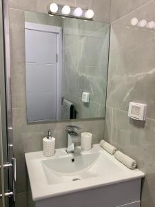 La salle de bains est pourvue d'un lavabo blanc et d'un miroir. dans l'établissement New 2 rooms flat fully equipped 5 min to Bat Yam beach near Tel Aviv, à Bat Yam