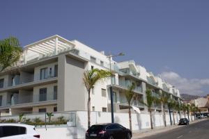 a building with palm trees in front of it at Apartamento en primera línea (Mejor clima de Europa). in Torrox Costa