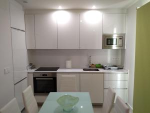 a kitchen with white cabinets and a table and a microwave at Apartamento en primera línea (Mejor clima de Europa). in Torrox Costa