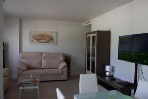 a living room with a couch and a flat screen tv at Apartamento en primera línea (Mejor clima de Europa). in Torrox Costa