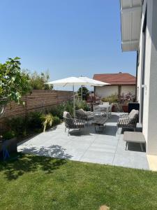 a patio with tables and chairs and an umbrella at Grande villa avec piscine sur la côte in Bursins