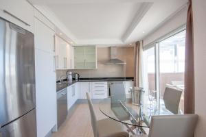 cocina con mesa de cristal y armarios blancos en Luxury penthouse, panoramic sea view, en Mogán