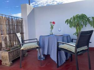 a table with two chairs and a vase of flowers on it at ATICO ALFAQUEQUE in Seville