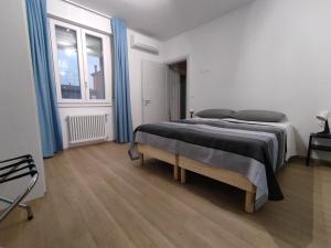 a bedroom with a large bed with blue curtains at Grigio Perla Panigale, villetta con giardino e parcheggio privato gratuito in Bologna