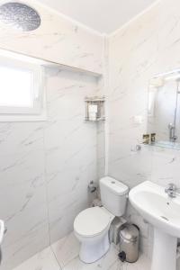 a white bathroom with a toilet and a sink at Apartment Duri in Pefkohori