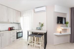 a white kitchen with a counter and stools in it at Apartment Duri in Pefkochori