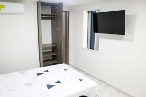 a room with a tv on the wall and a table at Apartaestudio moderno en Cali 1 in Cali