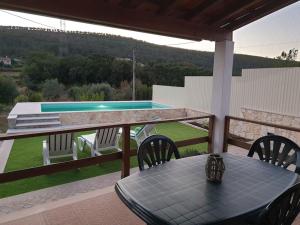 a table and chairs on a balcony with a swimming pool at Casa Pregueira in Lisboinha