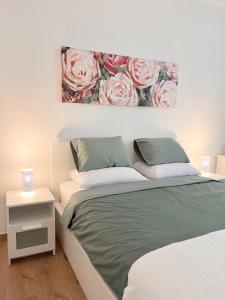 een slaapkamer met een bed en een schilderij van rozen bij Verde in Zagreb