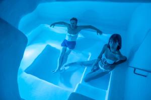 a man and a woman swimming in a blue pool at Trulli sul Mare Forcatella in Savelletri di Fasano +53 photos