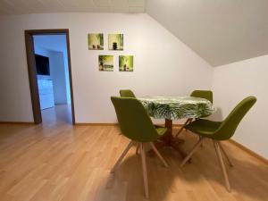 a table and four green chairs in a room at Ferienwohnung Bad Säckingen ruhig und zentral in Bad Säckingen