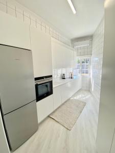 Biała kuchnia z białymi szafkami i urządzeniami w obiekcie Apartamento Cava do Viriato Deluxe w mieście Viseu