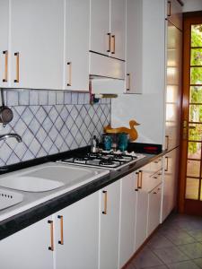 una cucina con armadi bianchi e piano cottura di Villetta mare di Sicilia a Fontane Bianche
