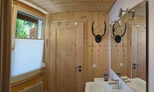 a bathroom with a sink and a mirror and antlers on the wall at Ruhiges Ferienhaus am Waldrand mit Sauna und Kamin in Langenbach