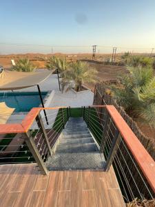 una escalera que conduce a una terraza con piscina y sombrilla en The Hidden Lodge en Al Ain