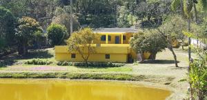a yellow house sitting next to a body of water at Bela Chácara in Suzano