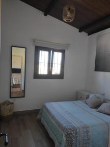 Habitación blanca con cama y espejo en Chalet cerca de la playa La Barrosa en Chiclana de la Frontera