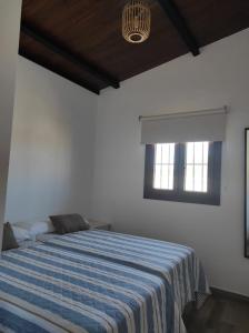 1 dormitorio con 1 cama con manta de rayas azules en Chalet cerca de la playa La Barrosa, en Chiclana de la Frontera
