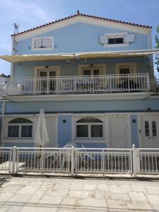 a blue house with a balcony and an umbrella at Alpha apartment, Ireon Samos in Ireon