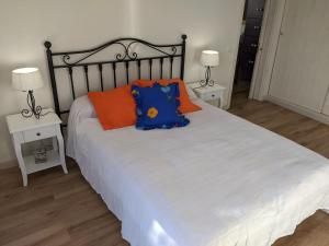Schlafzimmer mit einem Bett mit orangefarbenen und blauen Kissen in der Unterkunft La Casita del Sendero in La Guancha
