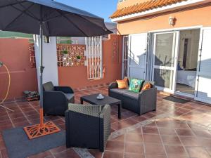 una casa con patio con sombrilla y muebles en La Casita del Sendero, en La Guancha