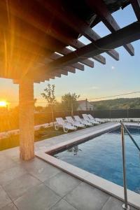 einen Pool mit Liegestühlen und Sonnenuntergang in der Unterkunft Villa Ante Škina in Sevid