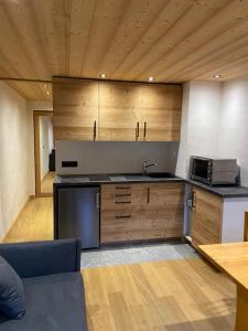 cocina con armarios de madera, fregadero y microondas en Studio face aux pistes, en Praz-sur-Arly