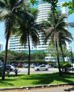 um parque de estacionamento com palmeiras em frente a um grande edifício em Cond. Mediterrâneo Flat no Rio de Janeiro