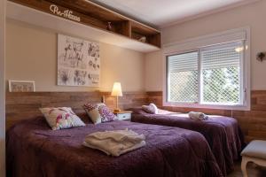 1 dormitorio con 2 camas con sábanas moradas y ventana en Estilo e Conforto a 300m da Rua Coberta de Canela, en Canela