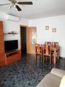 un soggiorno con tavolo, sedie e TV di Apartamento Bella Carmen : para 6 personas a Cunit