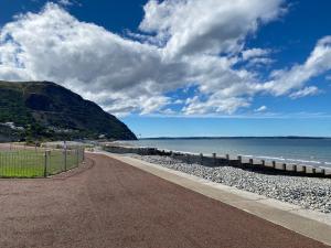 a path on a beach next to the water at Lovely New 2 Bedroom Condo with Stunning Seaviews in Penmaen-mawr