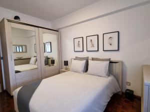 een slaapkamer met een groot wit bed en een spiegel bij Blue Boat House - The Atlantic Breeze in Nazaré