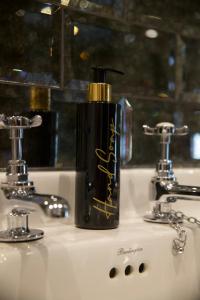 a black bottle of soap sitting on a bathroom sink at Mademoiselle's Boutique Holiday Accommodation in Whitby