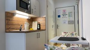 uma pequena cozinha com um lavatório e um micro-ondas em Myroom Business Apartment Nähe Messe München em Munique