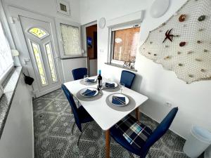 a dining room with a white table and blue chairs at Apartman Dino in Fažana