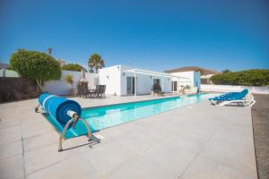 a pool with two blue chairs next to a house at Casa Conil with a private 25 meter heated pool in Conil