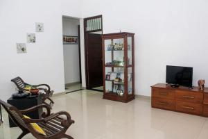 a living room with a tv and a chair and a cabinet at Arazia in Panadura