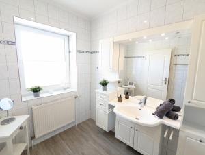 Baño blanco con lavabo y espejo en Das Inselhaus en Norddeich