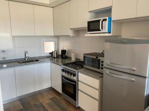 a kitchen with white cabinets and a stove top oven at BALCÓN AL RíO PARANÁ in Paraná