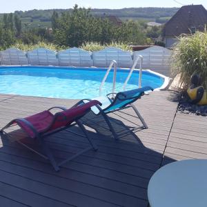 a pair of chairs sitting next to a swimming pool at Suite cocooning - Route des Vins in Bergbieten