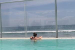 a woman sitting in a swimming pool looking out at the ocean at Hotel Del Mar Mancora in Máncora