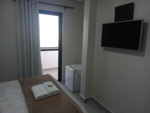 a bedroom with a bed and a flat screen tv at Hotel Solar Vitória in Vitória da Conquista