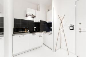 una cocina blanca con armarios blancos y azulejos negros en Project Comfort Apartament Dywizjonu 303 175/8 Warszawa, en Varsovia
