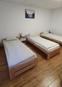 two beds in a room with wooden floors at KOKON Noclegi Żuromin in Żuromin