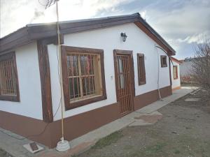 a small white building with wooden windows and a street at Mi Refugio in Río Gallegos