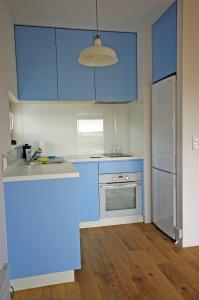 a blue kitchen with a sink and a refrigerator at Błękitny domek in Darłowo