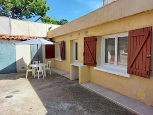 a patio with a table and an umbrella next to a building at appartement T2 AGDE centre à 10 mn des plages in Agde