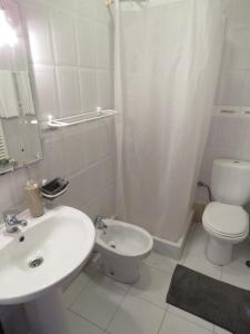 a white bathroom with a sink and a toilet at Casas da praia Supertubos in Peniche